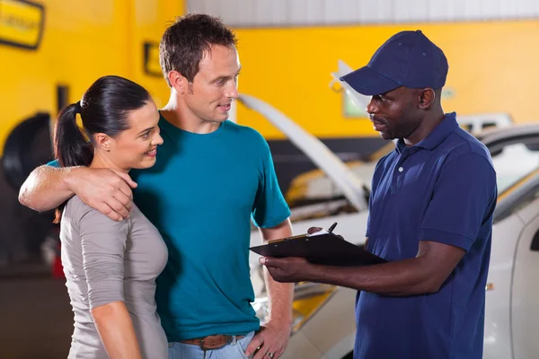 Mécanicien automobile parler à jeune couple — Photo