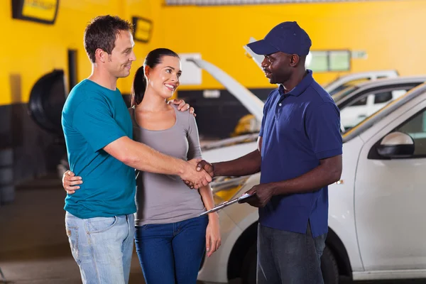 Auto técnico handshaking com casal — Fotografia de Stock