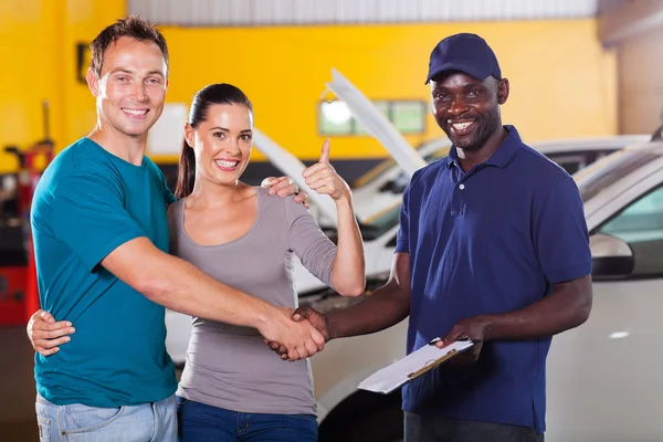 Joven pareja dando pulgar hasta a taller de reparación de automóviles — Foto de Stock