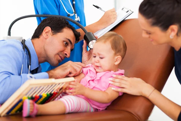 Médico pediátrico examinando o ouvido de um bebê doente — Fotografia de Stock