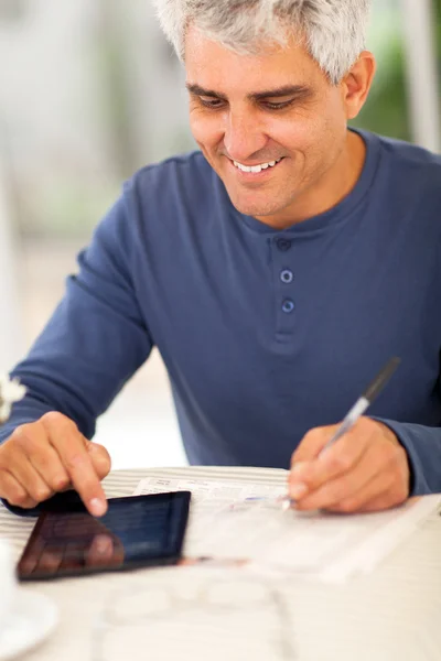 Homem de meia idade lendo jornal e fazendo notas — Fotografia de Stock