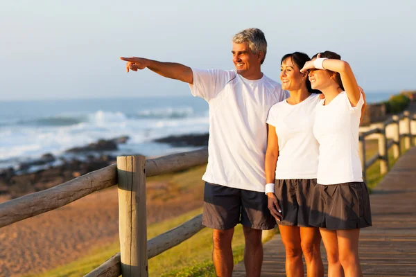 Middle aged man pointing at ocean with family — Stock Photo, Image