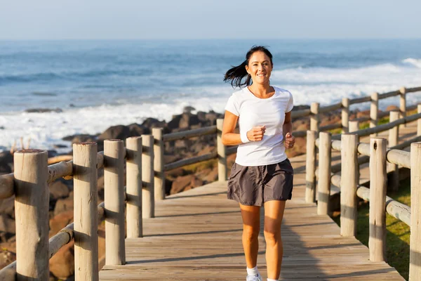 Frau mittleren Alters joggt am Strand — Stockfoto