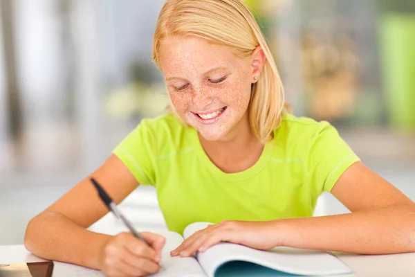 Happy preteen girl writing homework — Stock Photo, Image