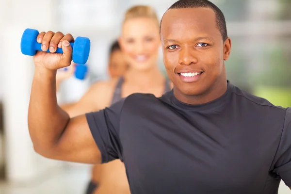 Uomo africano che si esercita in palestra con manubri — Foto Stock