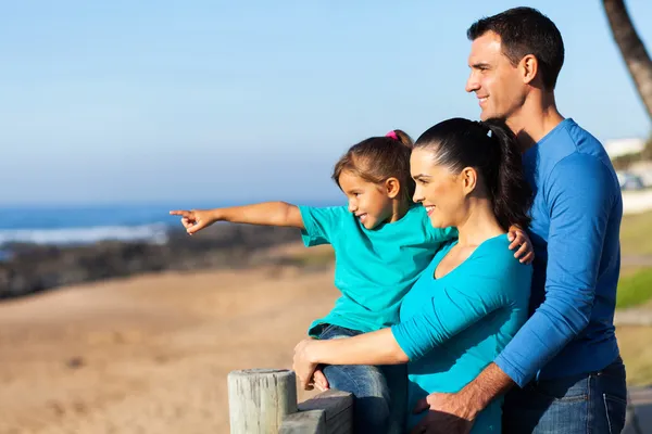 Liten flicka pekar på ocean med föräldrar — Stockfoto