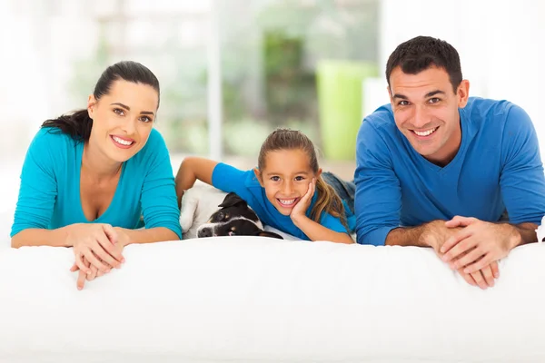 Familia feliz acostado en la cama con perro mascota —  Fotos de Stock