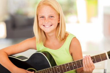 pre teen girl practicing guitar at home