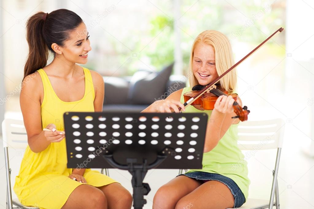 music teacher tutoring young girl to play violin