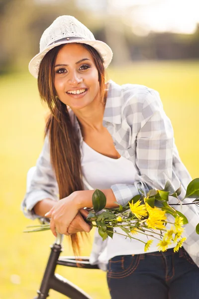 Jonge vrouw met bloemen poseren naast een fiets — Stockfoto