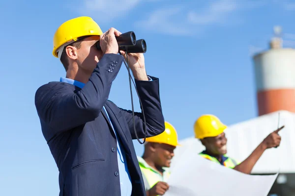 Arquitecto usando prismáticos mirando el sitio de construcción — Foto de Stock