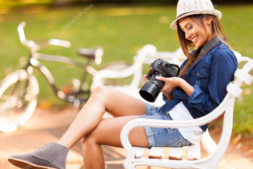 Pretty female student photographer checking photos on her camera