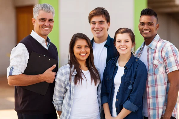 Manliga gymnasielärare står med studenter — Stockfoto