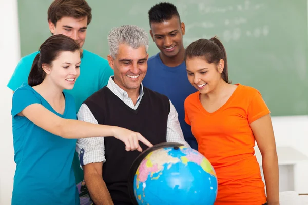 Middelbare scholieren en leraar kijken naar globe — Stockfoto