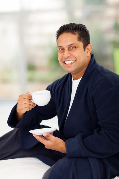 Indian man drinking coffee on bed — Stock Photo, Image