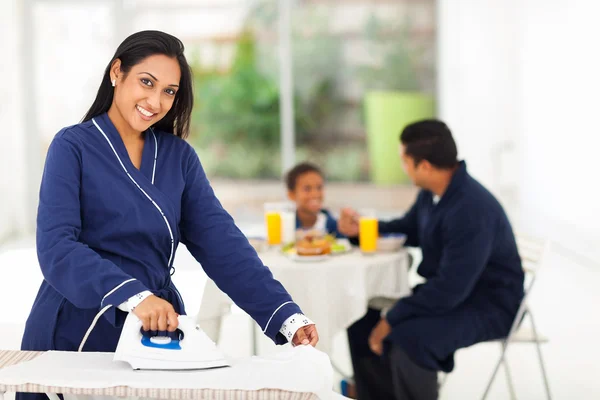 Mujer india planchando mientras marido e hijo desayunando —  Fotos de Stock