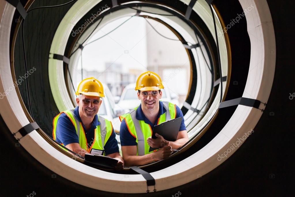 Warehouse workers standing between industrial tires