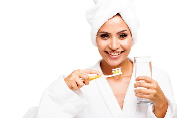 Young woman in bathrobe brushing teeth — Stock Photo, Image