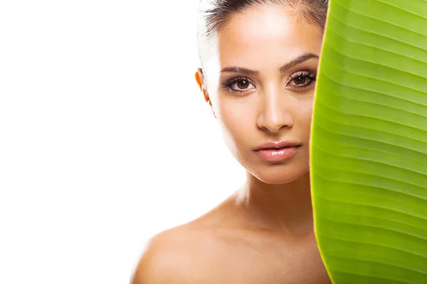 Fresh clear face of young woman behind green leaf — Stock Photo, Image