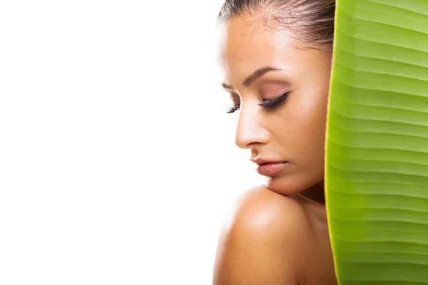 Young woman with eyes closed behind large green leaf — Stock Photo, Image