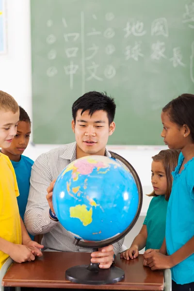 Ученики начальных классов и учителя, глядя на земной шар — стоковое фото