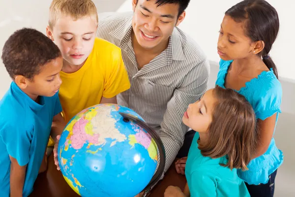 Schülergruppe mit Lehrer blickt auf den Globus — Stockfoto