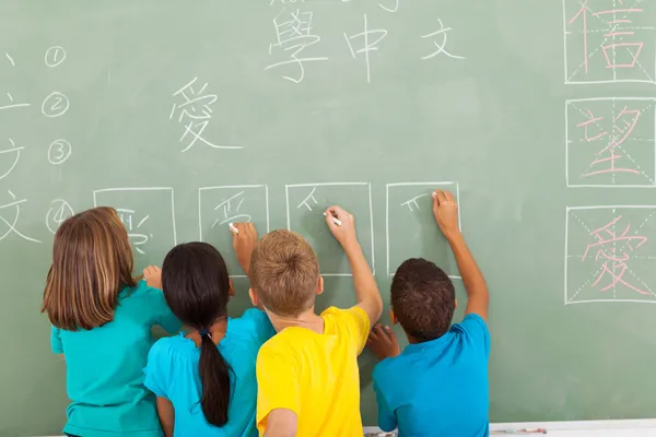 学生学习汉语写作在黑板上后视图 — 图库照片
