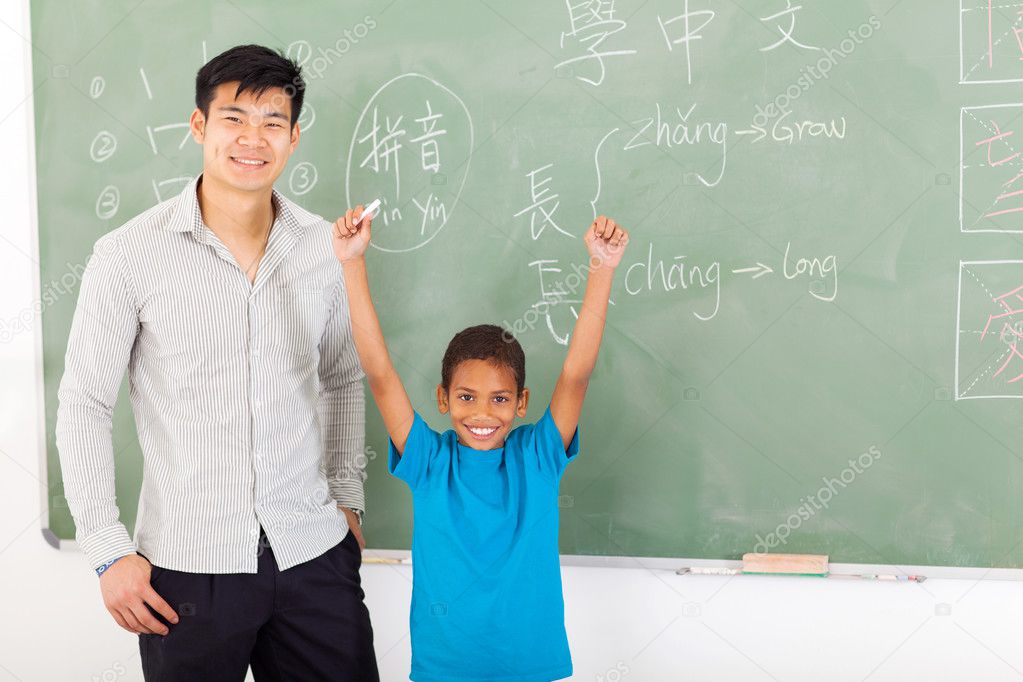 african boy with hands up after writing answer on chalkboard
