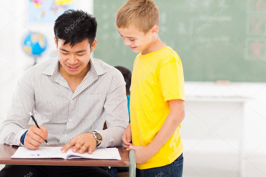 Young male teacher grading school boy's work