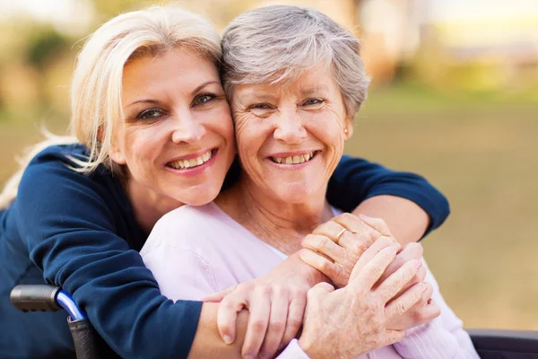 Frau mittleren Alters umarmt behinderte Seniorin — Stockfoto
