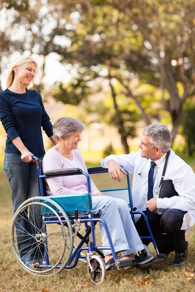 Midden leeftijd gezondheidszorg werknemer praten met senior gehandicapte pati — Stockfoto