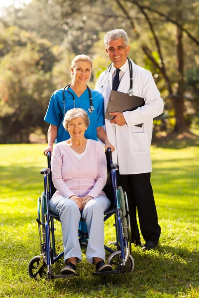 Werkers in de gezondheidszorg buitenshuis met handicap senior patiënt — Stockfoto