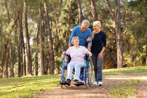 Coppia che porta la madre anziana disabile a fare una passeggiata — Foto Stock