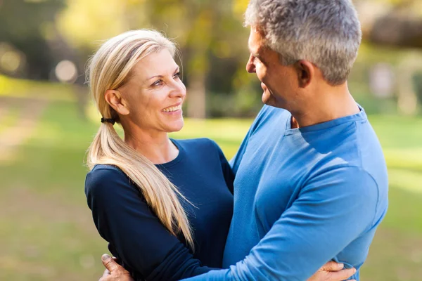 Midden leeftijd paar omarmen buitenshuis — Stockfoto