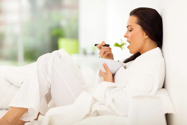 Mujer en la cama comiendo ensalada verde fresca —  Fotos de Stock