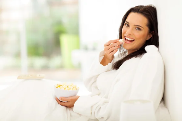 Woman eating popcorn on bed — Stock Photo, Image