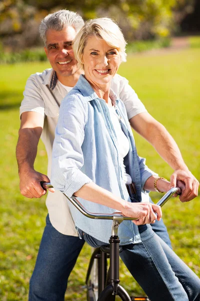 Casal sênior em uma bicicleta ao ar livre — Fotografia de Stock