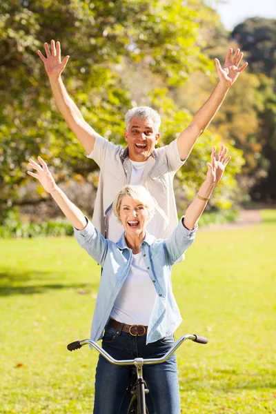 Playful senior couple having fun riding bicycle outdoors — Stock Photo, Image