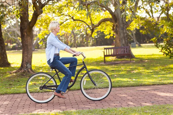 Ältere Frau fährt Fahrrad im Park — Stockfoto