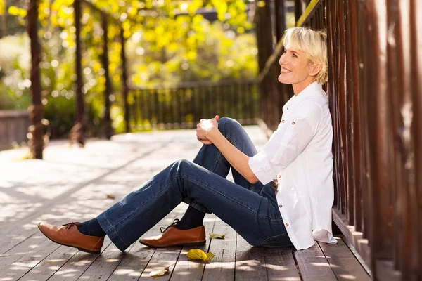 Feliz mujer de mediana edad sentado al aire libre — Foto de Stock