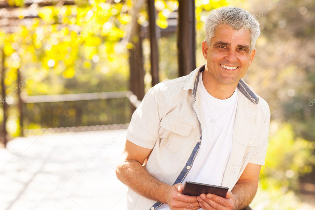 senior man holding tablet computer outdoors