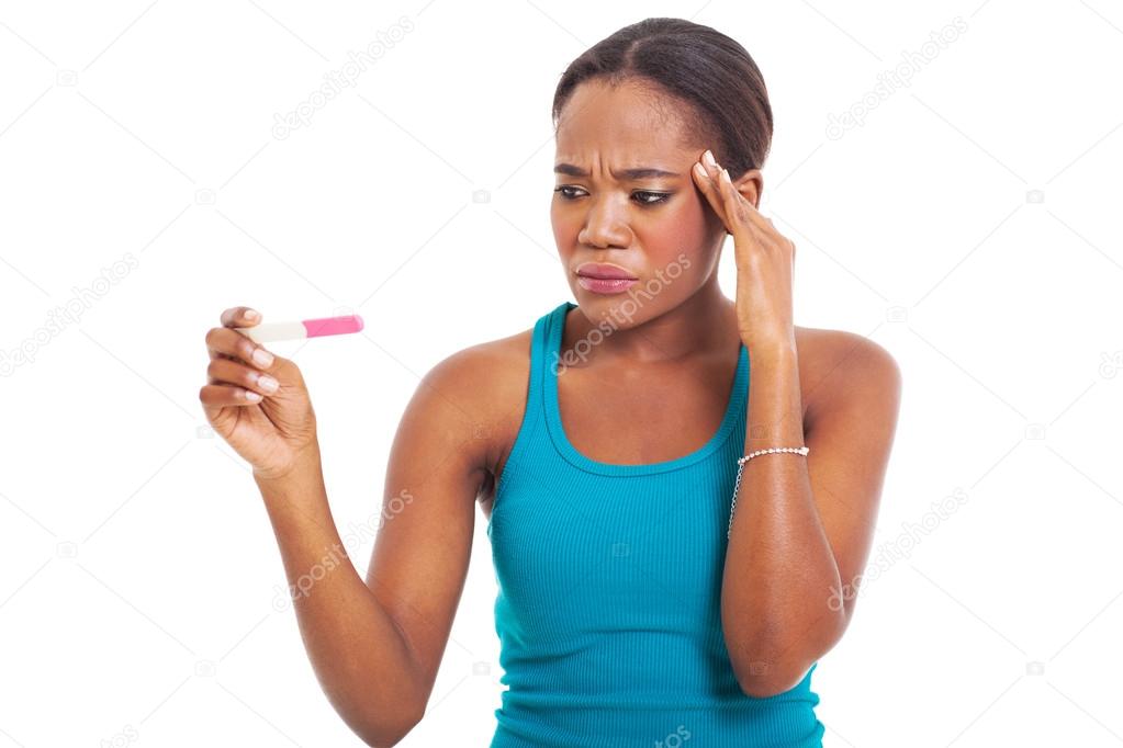 confused african woman looking at pregnancy test
