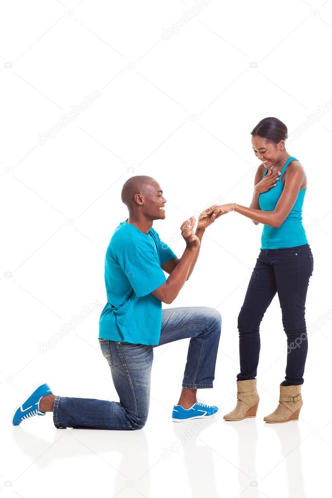African man putting engagement ring on his girlfriend after she