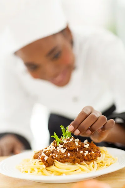 Female african cook garnishing spaghetti — Stock Photo, Image