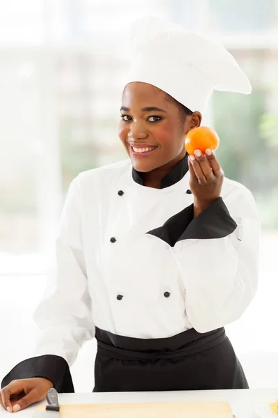Unga kvinnliga afrikanska kocken håller tomat — Stockfoto