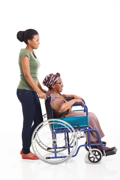 Joven africana mujer empujando abuela en silla de ruedas —  Fotos de Stock