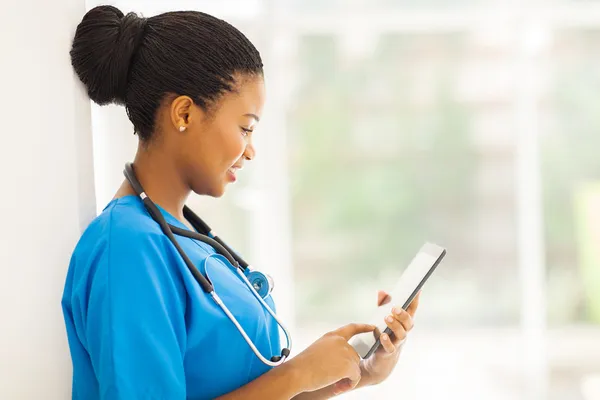 Ung amerikansk medicinsk arbetstagare använder Tablet PC: n使用平板电脑的年轻非洲裔美国医务工作者 — Stockfoto