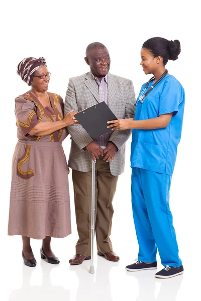 Young african nurse talking to senior couple — Stock Photo, Image