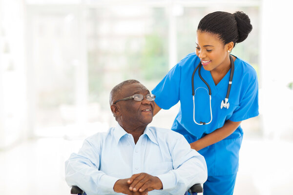 african nurse taking care of senior patient in wheelchair