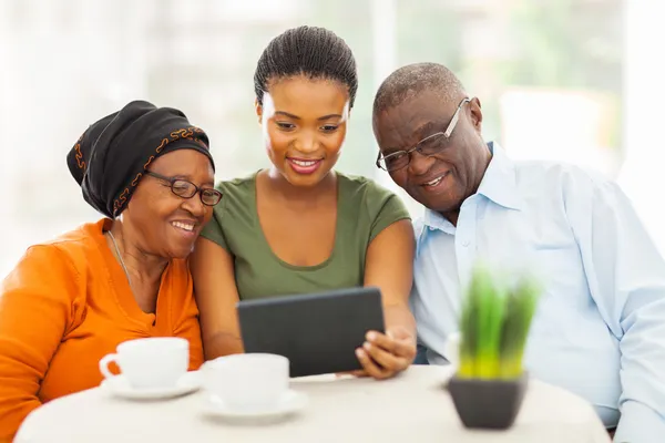 Muchacha africana adulta joven con los padres mayores usando la tableta comput —  Fotos de Stock